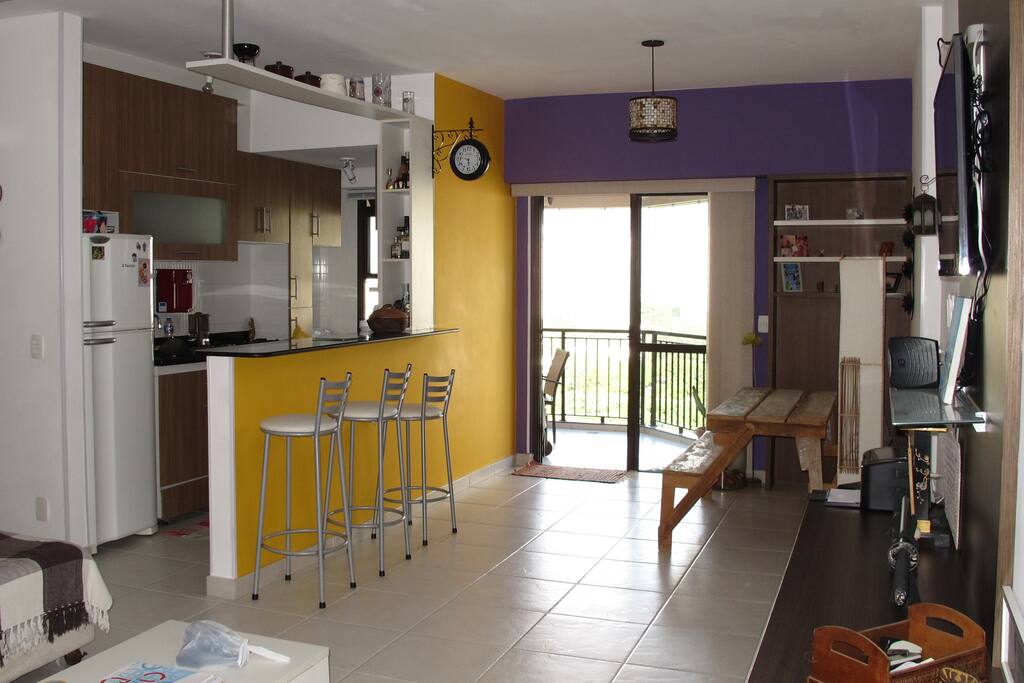 Sala ampla, cozinha americana. Sofá espaçoso e decoração alegre.
