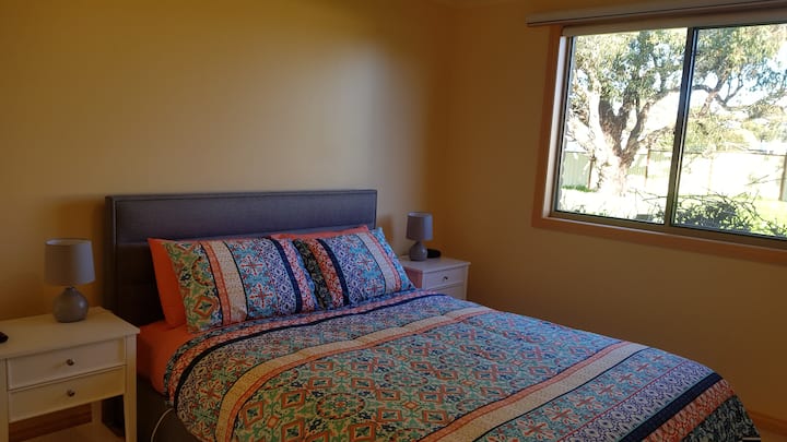 dormitorio, con cama tamaño queen, manta eléctrica y televisión.
