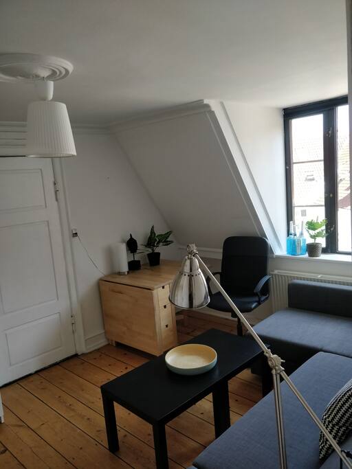 The second room have a large sofa, an extendable table, a cabinet, shelfs and coat hangers.
