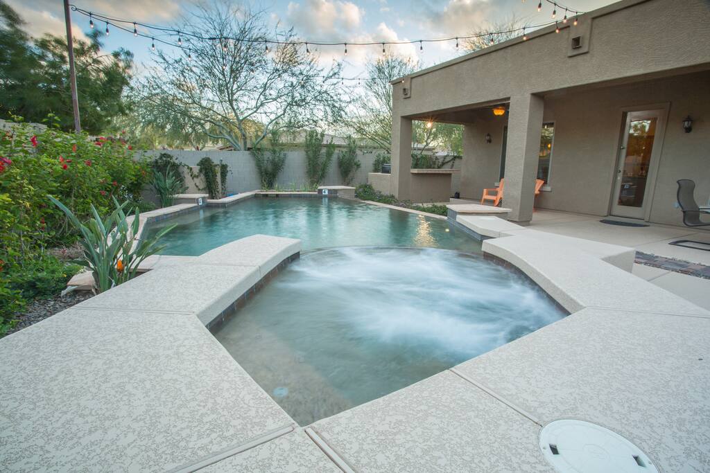 view from the spa - negative pool edge, lush landscape & bistro lights overhead