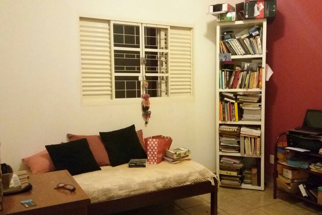 Quarto individual com biblioteca e mesa de trabalho.