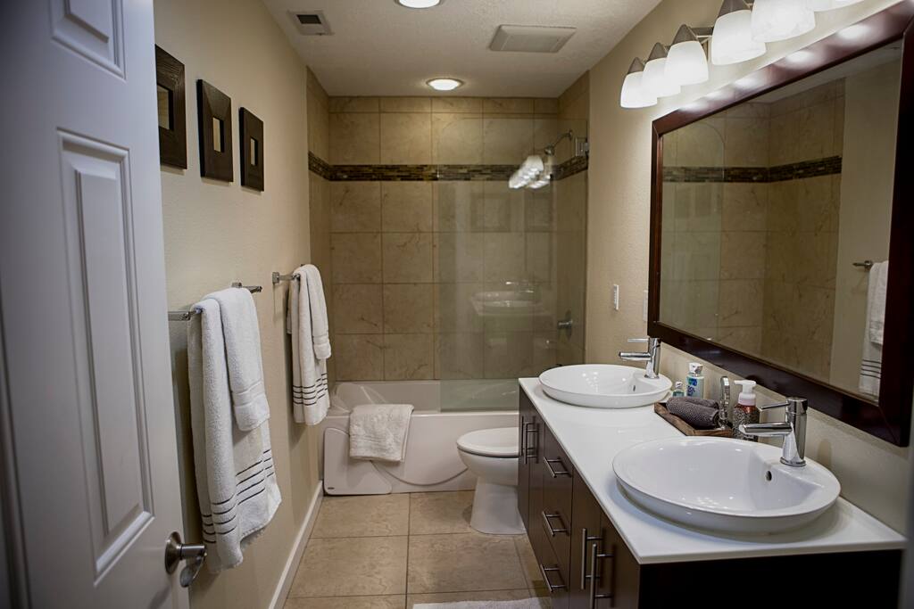 Private guest bath with dual vanity, shower, and a jetted tub.