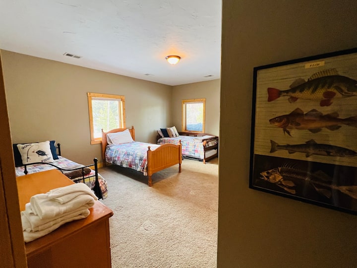 Camera da letto seminterrata con tre letti singoli e un futon.