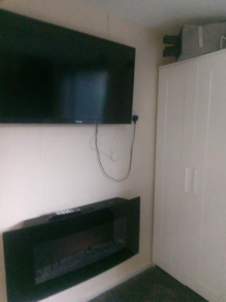 Una acogedora chimenea y un televisor en el dormitorio doble: coloca la cuna de viaje guardada encima del armario también.