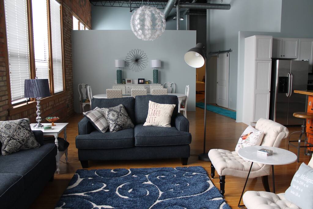 Living room with dining room behind, kitchen to the right, and bedrooms through the hallway behind.