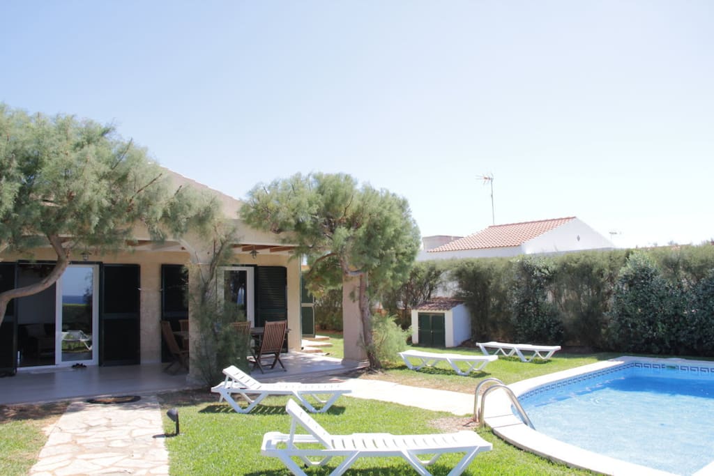 Fachada de la villa, terraza y piscina con mobiliario exterior
