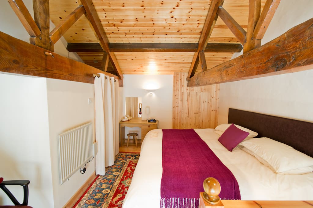 Loft style beamed bedroom and shower room with shower, toilet and basin.
