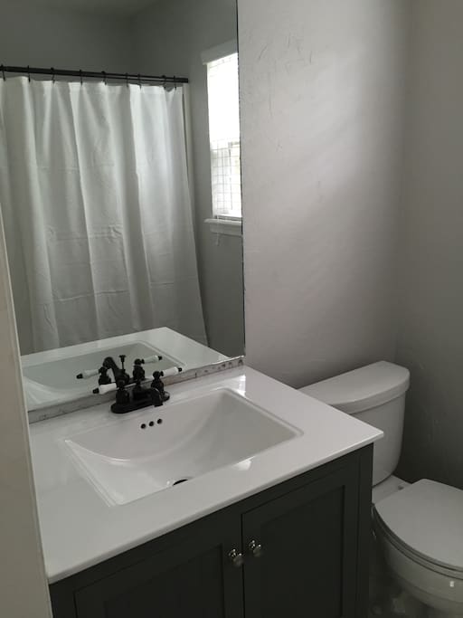 Renovated bathroom with new vanity, toilet, and modern flooring.