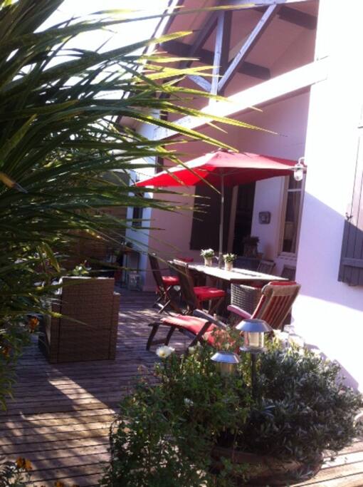 Coin repas sur terrasse avant fleurie et salon de jardin