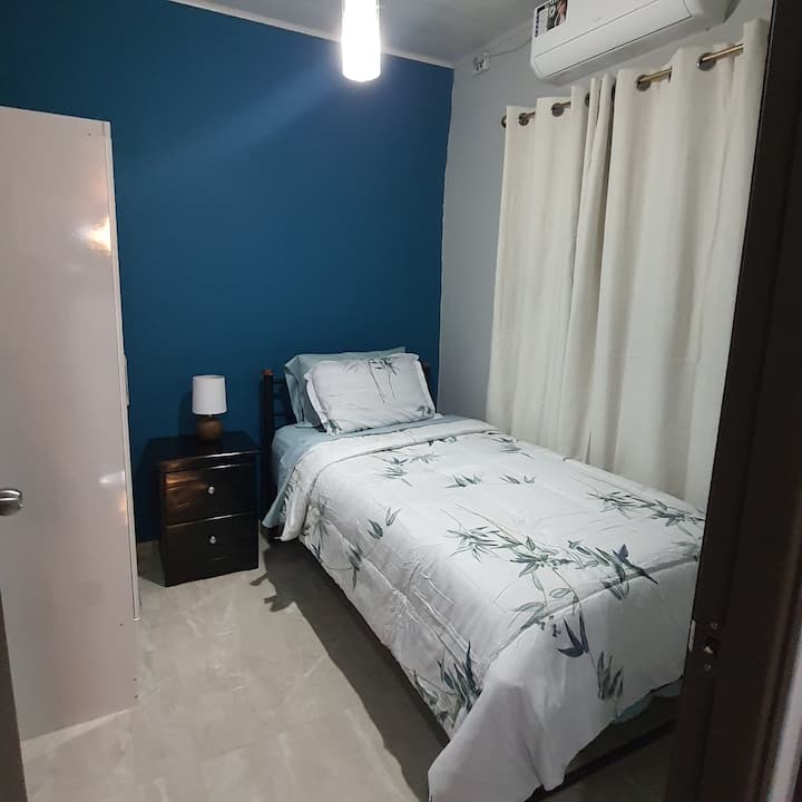 Проста спалня за един гост. Двойно легло, малък килер, нощна маса, лампа, климатик.