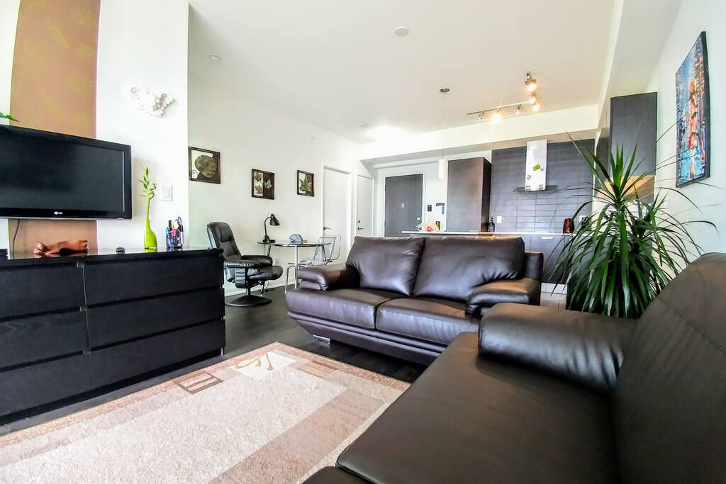 Cozzy living room, kitchen behind leather sofa, tv, drawer, dinning/computer table.