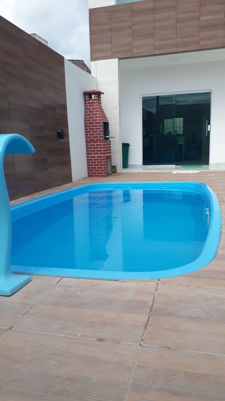 A private swimming pool is set within a tiled area, featuring a contemporary design with a smooth, curved edge. The water appears clear and inviting. Adjacent to the pool, a wall with a natural wood finish provides a warm backdrop, enhancing the tranquil setting.