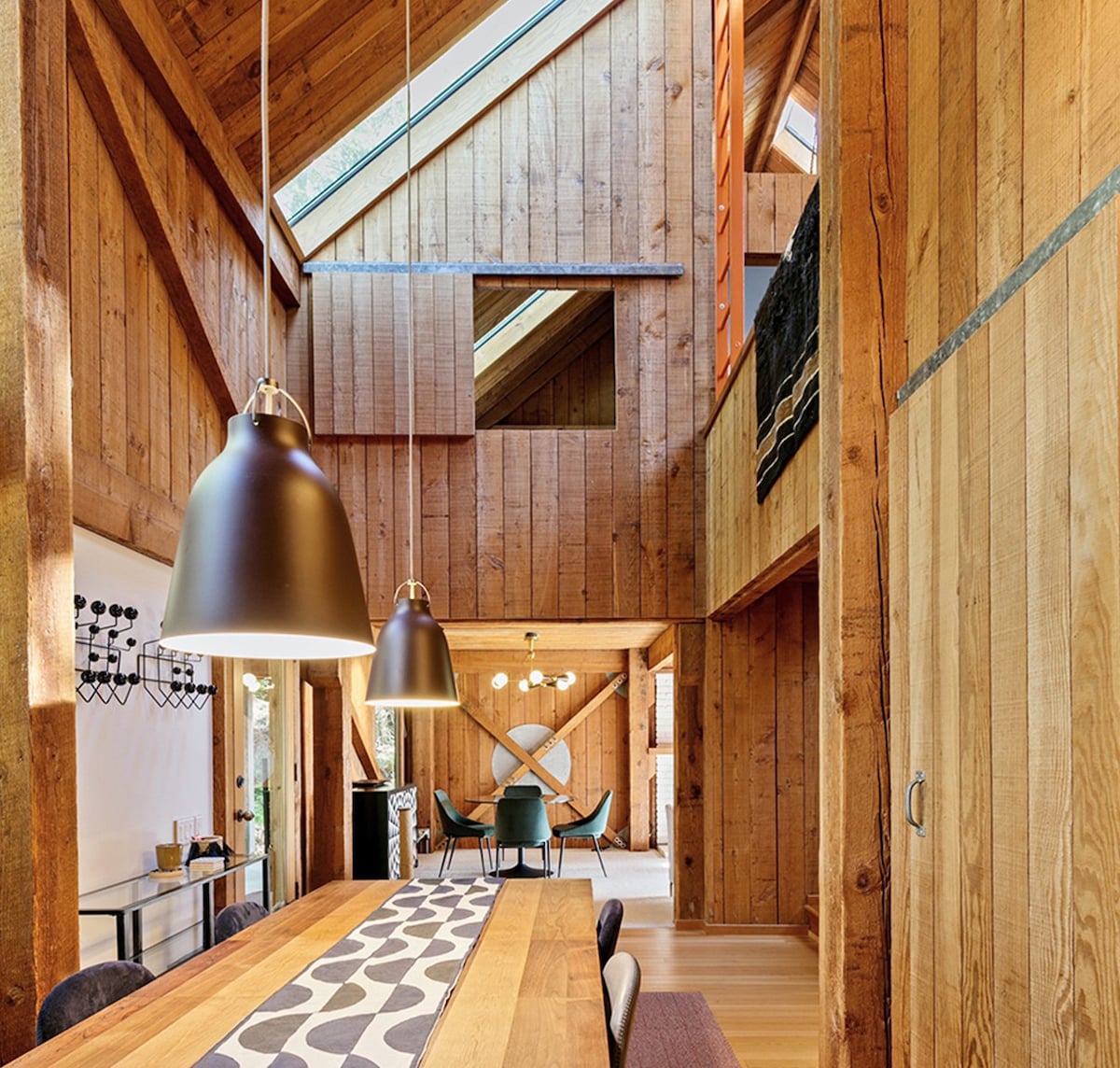 A minimalist yet cozy-looking wooden interior of a dining area is pictured, within a home designed by William Turnbull Jr.