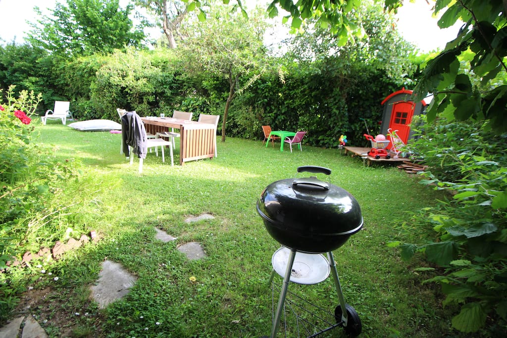 Jardin de 200 m², avec tables, chaises, bains de soleil, coussins et jeux pour enfants.