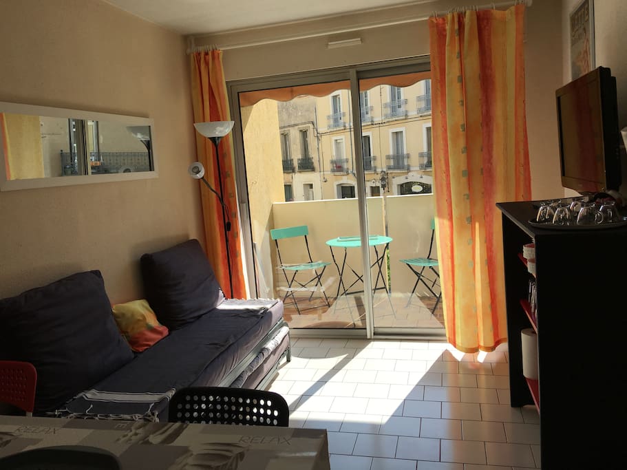 coin salon tv avec lit convertible donnant sur petite terrasse