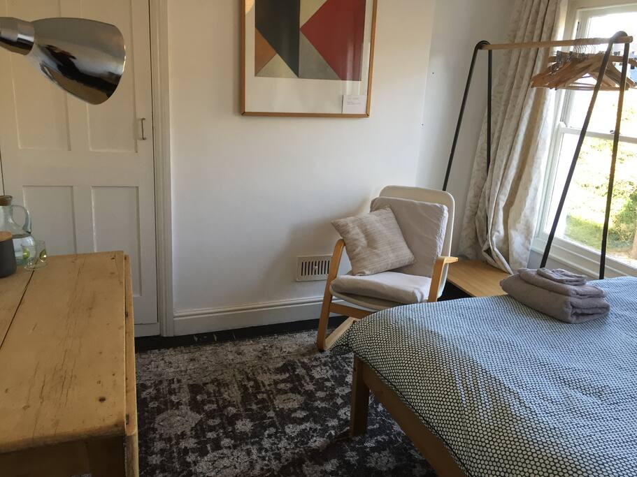 There is a clothes rail and a cupboard full of shelves. The top shelf houses the hair dryer, iron, fan, bed linen.