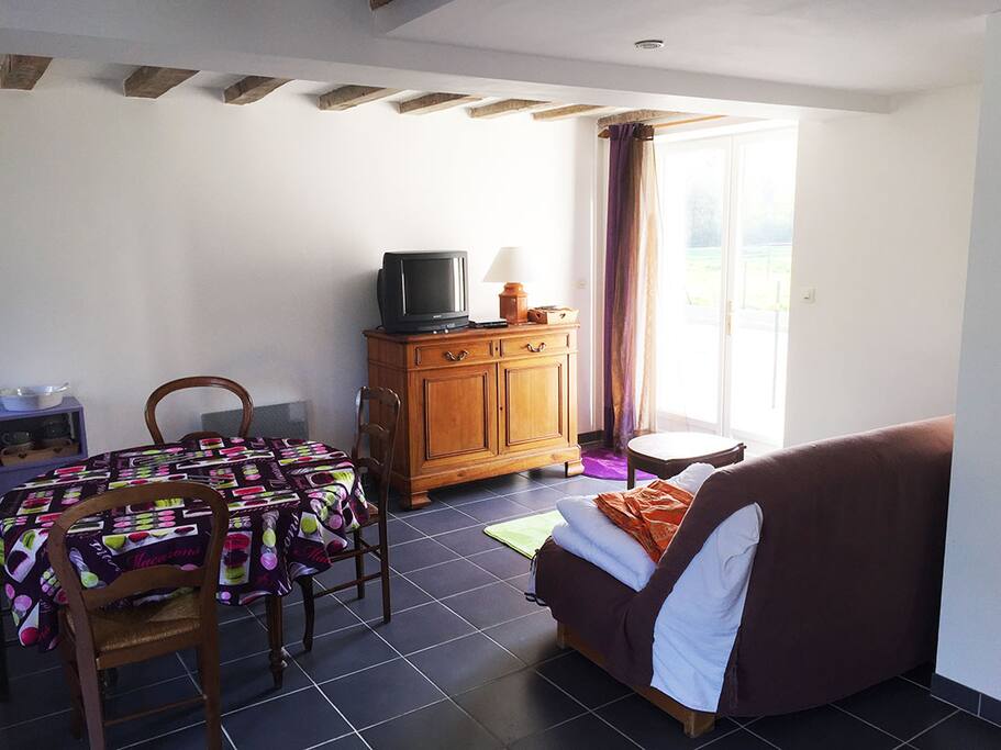 Au rez-de-chaussée, le séjour, la table à manger et la cuisine. La porte fenêtre donne sur la terrasse privative. Un clic-clac permet ici de coucher 2 personnes en appoint !