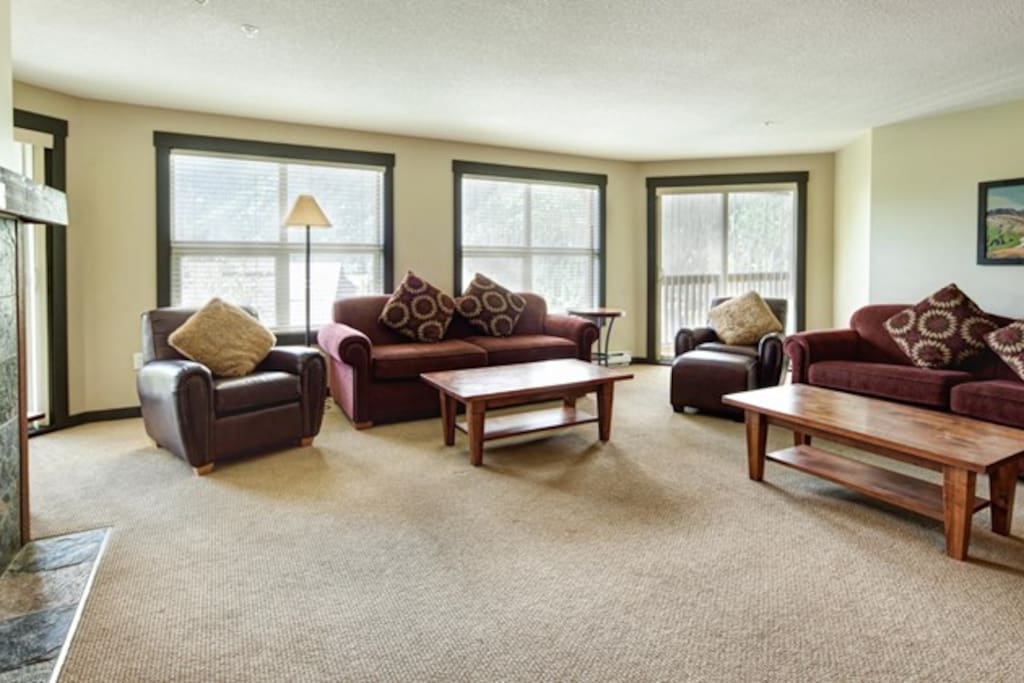 The cozy living room features large windows and a fireplace