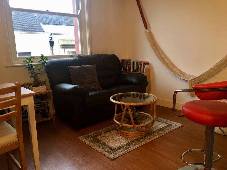 The living room includes a small dining table for 2, a sofa, a bean bag, a coffee table and a bar stool.