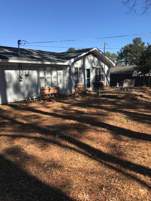 Fenced in backyard with charcoal grill.