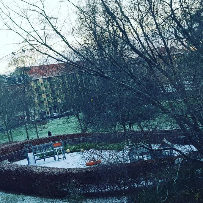Udsigten fra lejligheden udover parken med legeplads osv.