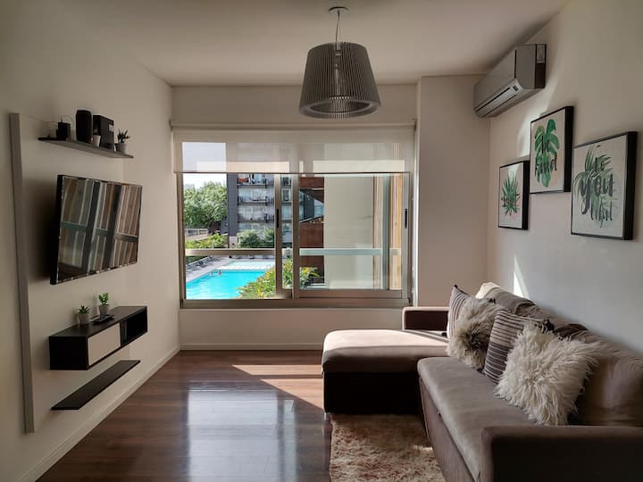 Sebule yenye kiyoyozi, televisheni janja na kitanda cha sofa mbili.