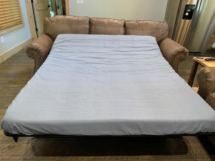 Manželská pohovka v rodinnej izbe. Posteľná bielizeň, vankúše a flísová prikrývka sú pripravené na použitie a sú v šatníku hlavnej spálne.