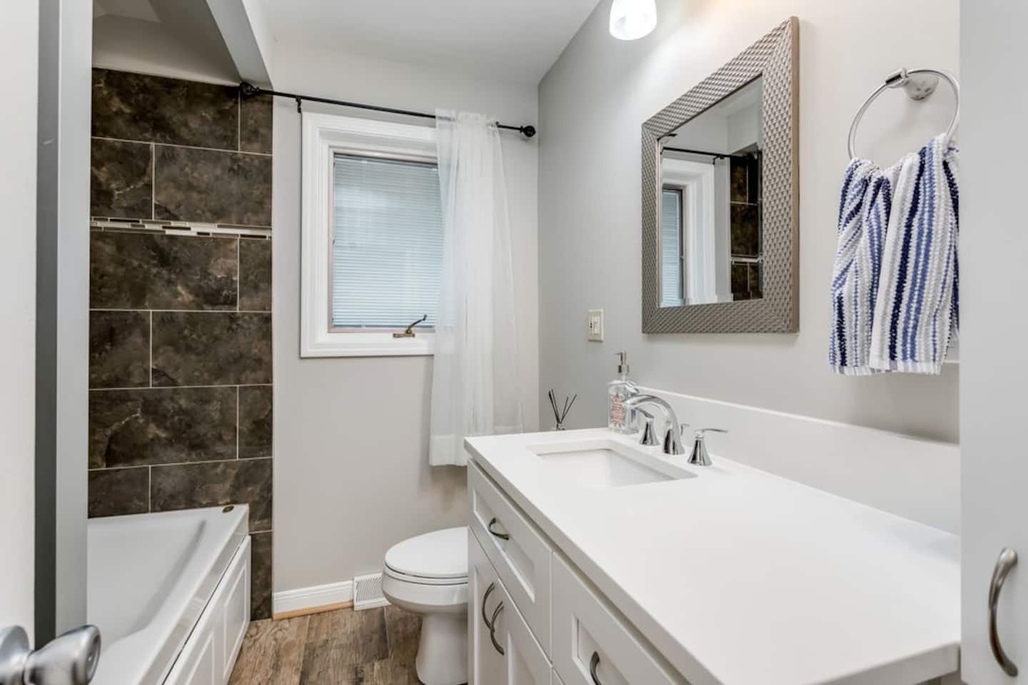 A clean and spacious bathroom featuring tub, a walk-in shower and vanity.