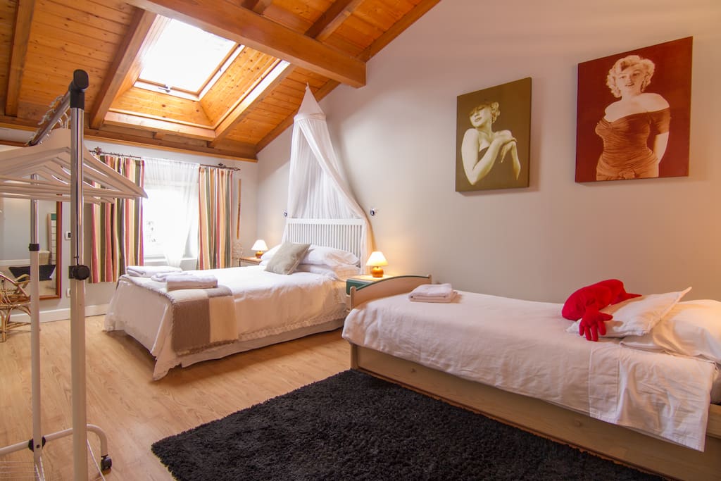 Una habitación abuhardillada, con altos techos de madera, una ventana y una claraboya