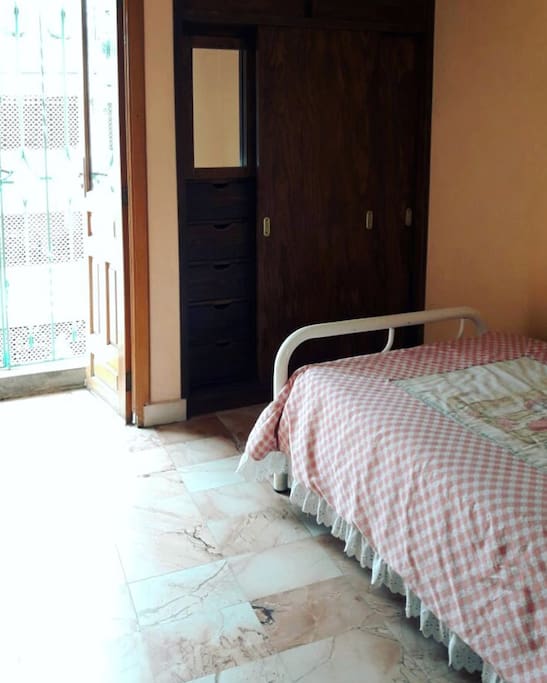 Recámara para una persona con balcón, clóset, ventilador de tocador y ropa de cama incluidos.