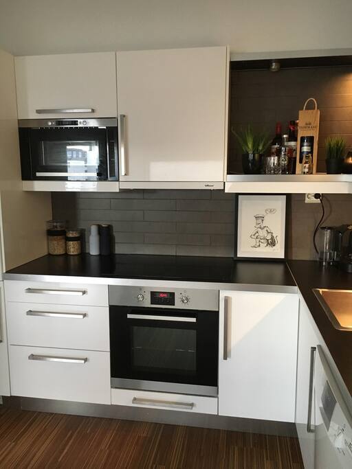 Kjøkken med hvitevarer, komfyr, mikrobølgeovn og nespressomaskin.