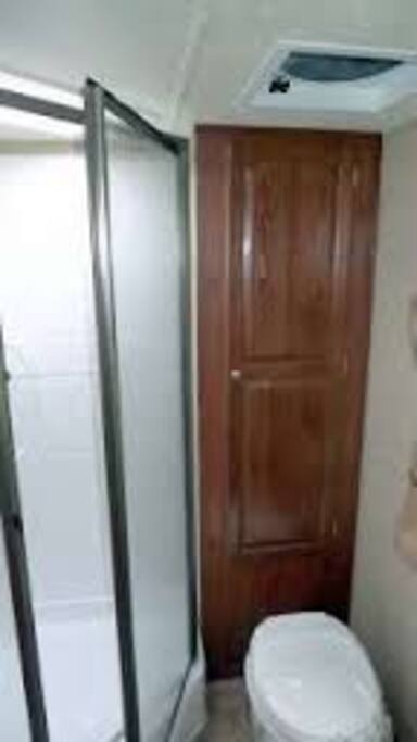 Bathroom has large sunny window (tinted w/blinds) and glass shower door