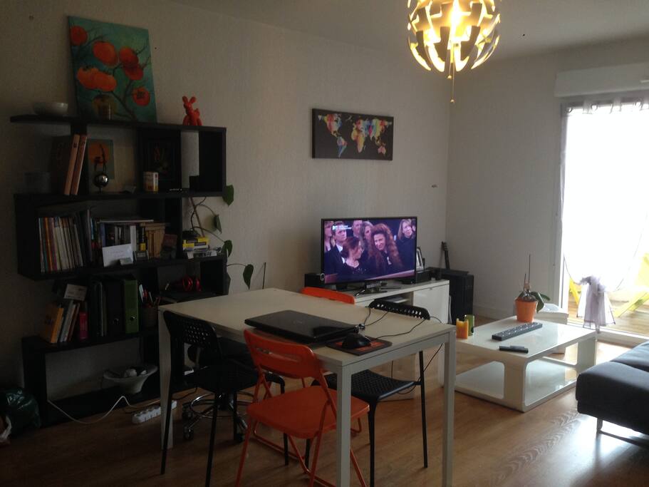 Salon/salle à manger ouvert sur la cuisine et donnant sur un balcon.