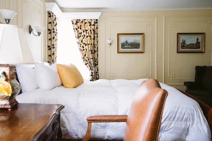 ห้องนอนใหญ่เตียงคิงไซส์เก้าอี้หนังและโต๊ะโบราณ