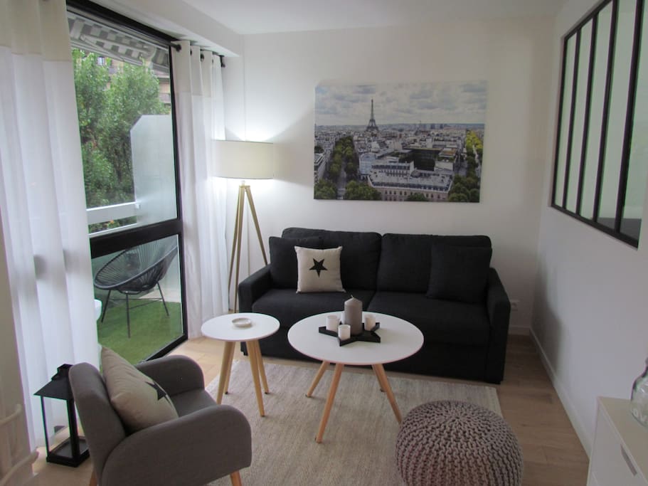 Salon lumineux avec télévision, fauteuil et canapé bordant l'agréable la terrasse.