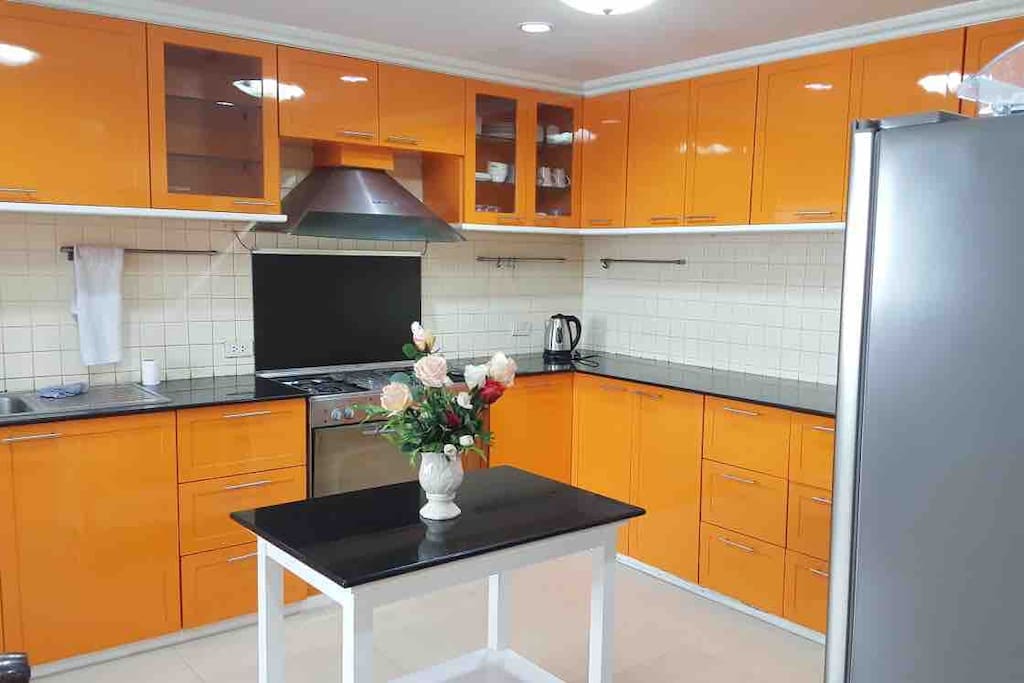 The fully equipped kitchen with refrigerator, microwave, stove, oven, kettle, utensils and pots and pans.