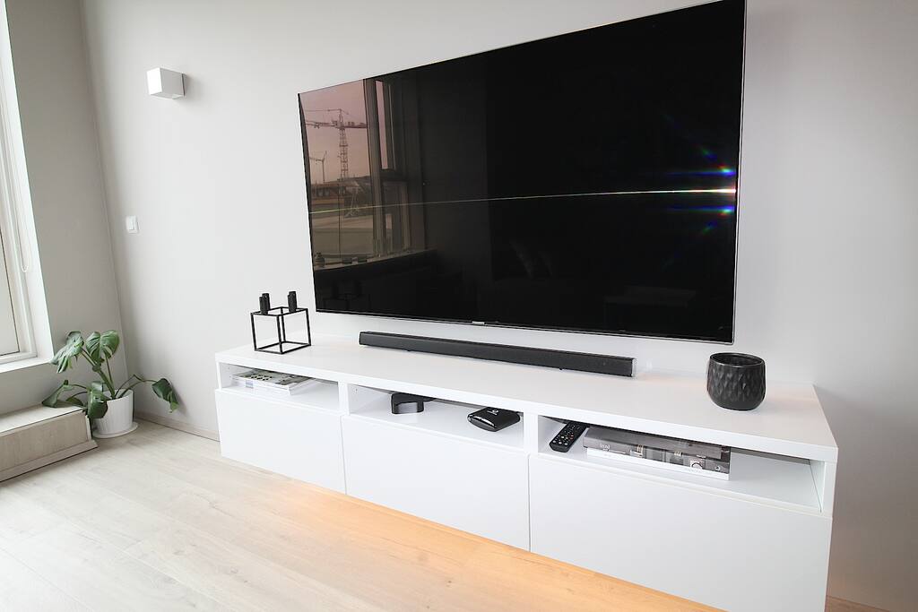 There is a 65 inch Samsung smart TV with access to Netflix in the living room.