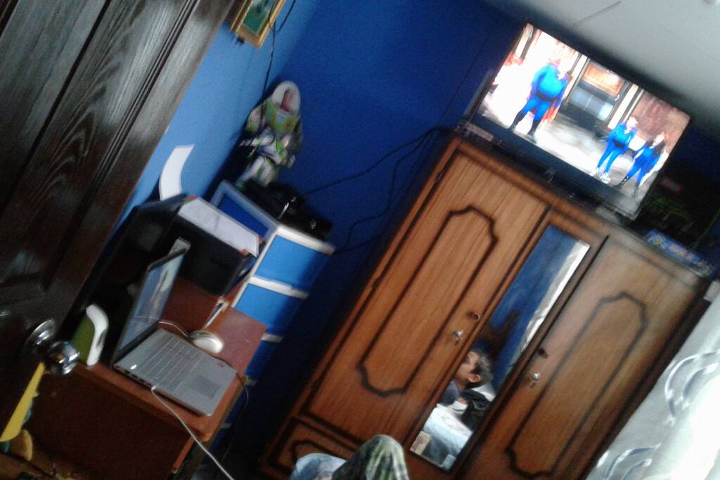 Cuarto con cama individul. Con pantalla y escritorio y computadora.