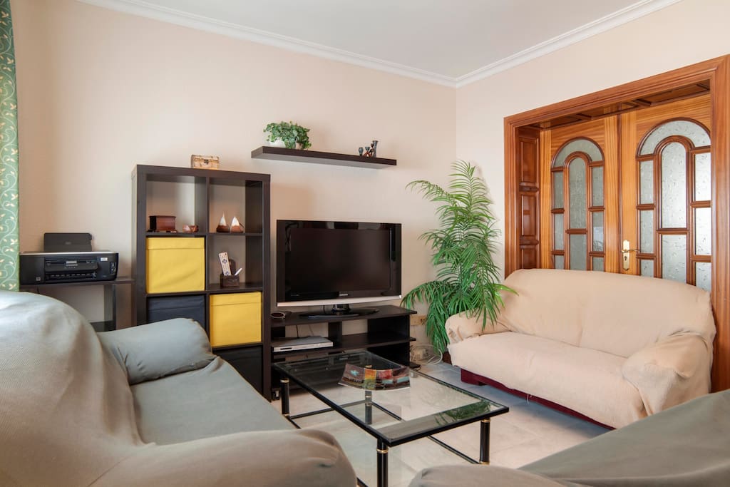 Salón muy amplio con tres sofás y dos balcones al exterior