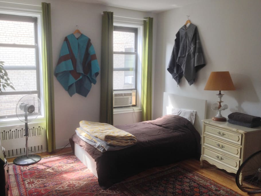 Spacious bedroom with lots of natural light, storage space, and art-filled decor.
