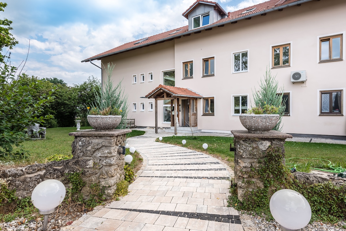 The entrance to the property is framed by a pathway made of stone pavers, leading to a welcoming doorway. Decorative planters filled with greenery are positioned on either side of the path, while spherical lights line the walkway, creating an inviting approach to the building.