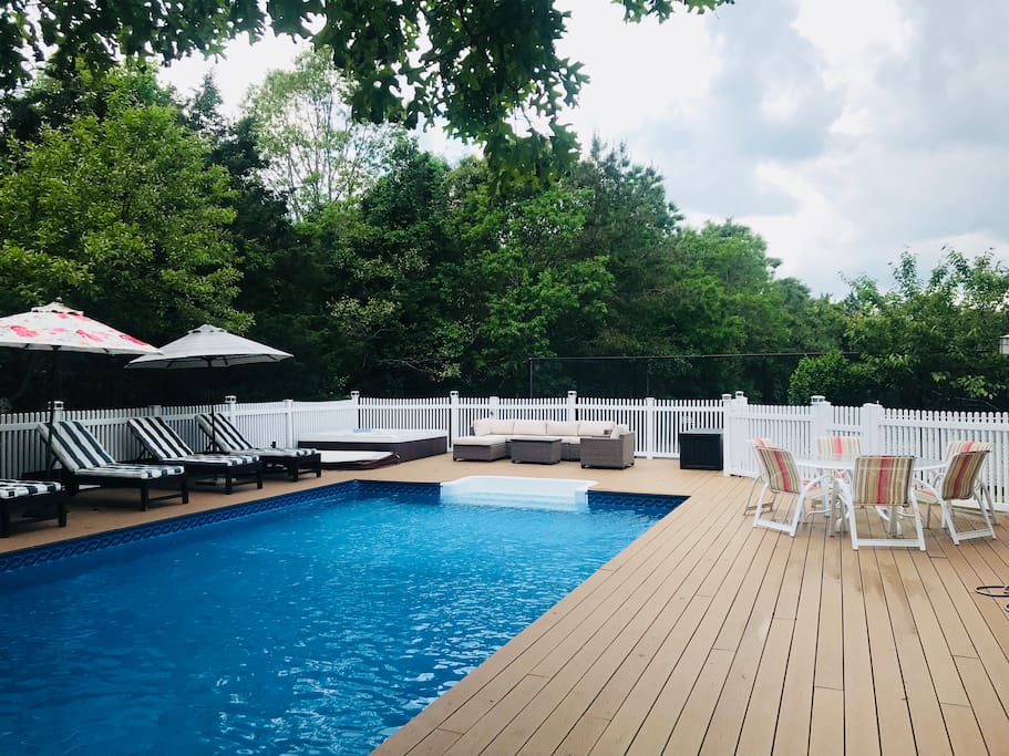 Heated pool with hot tub. Sun-filled deck with poolside loungers, umbrellas, BBQ grill, outdoor dining table and outdoor lounge area.
