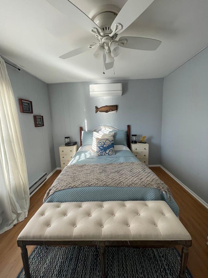 غرفة نوم في الطابق السفلي مع سرير كامل ومكيف هواء