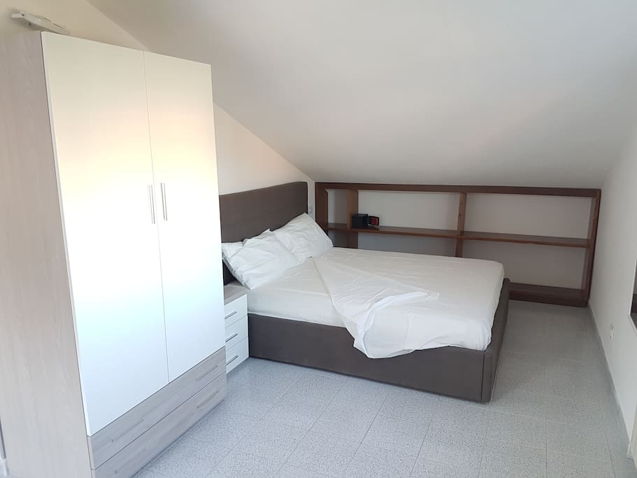 Camera con letto matrimoniale con armadio a due ante con 2 cassetti, comodino, specchio e mensole