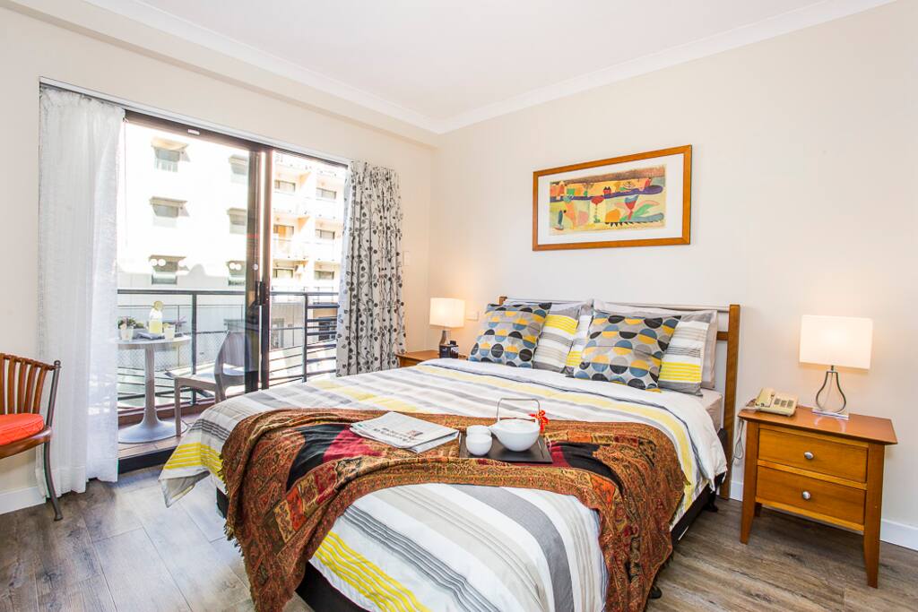A bright and airy bedroom with a balcony that overlooks the tennis court