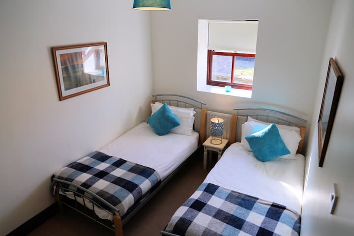 Chambre à deux lits au rez-de-chaussée avec matelas et armoire Emma confortables.  Il y a deux marches en pierre pour accéder à cette chambre.