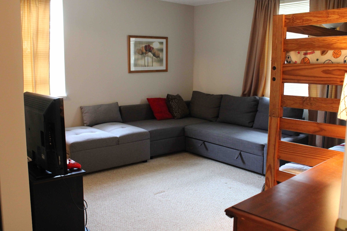 غرفة نوم رئيسية مع أسرّة بطابقين ، وسرير بحجم وسط (أريكة زرقاء )، وسرير مزدوج قابل للسحب (أريكة رمادية).