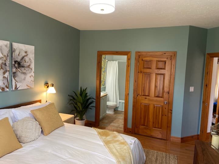 غرفة نوم رئيسية فاخرة مع حمام داخلي وسرير كينج. تلفزيون عالي الدقة وإطلالات على الحديقة من النافذة.