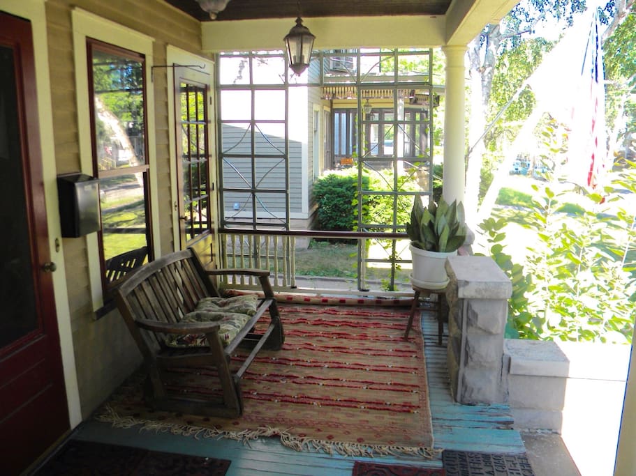 Large comfortable front porch with glider bench and space for table and chairs.
