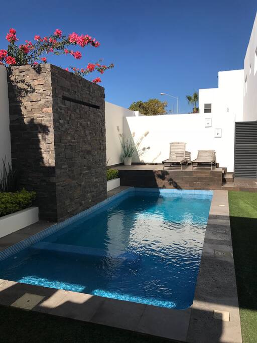 Alberca con chapoteadero, cascada, camastros y tv